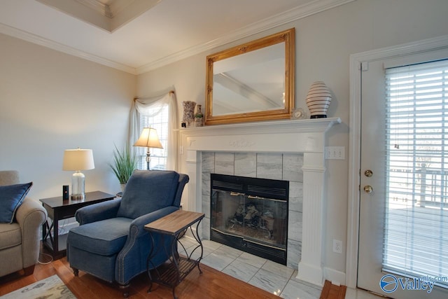 sitting room with a tile fireplace and crown molding