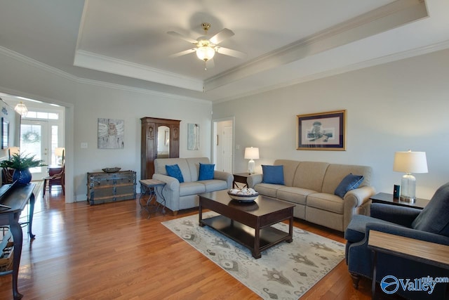 living area featuring ceiling fan, a tray ceiling, wood finished floors, and ornamental molding