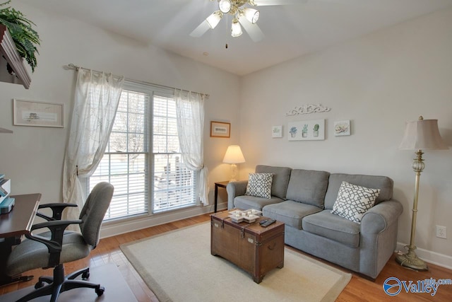 living area with baseboards, light wood finished floors, and ceiling fan