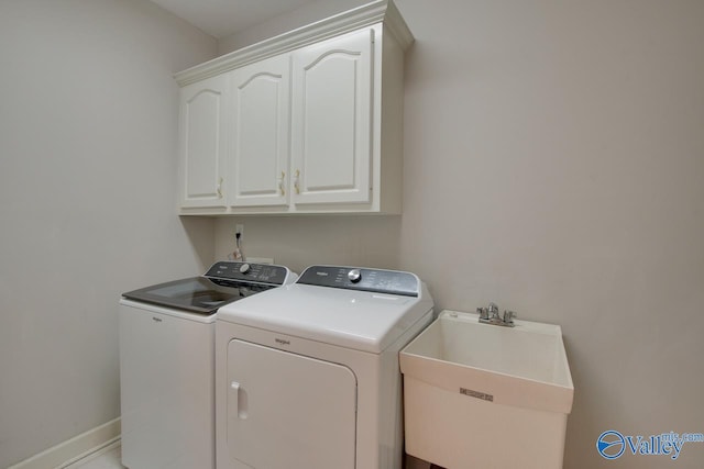 laundry area with washer and clothes dryer, cabinet space, baseboards, and a sink