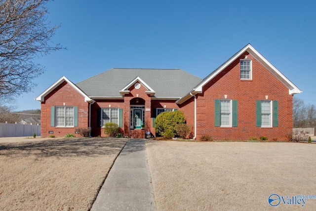 view of front of house with fence, brick siding, roof with shingles, and crawl space