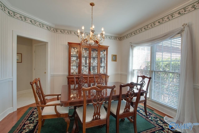 dining room with a notable chandelier, wood finished floors, baseboards, and ornamental molding