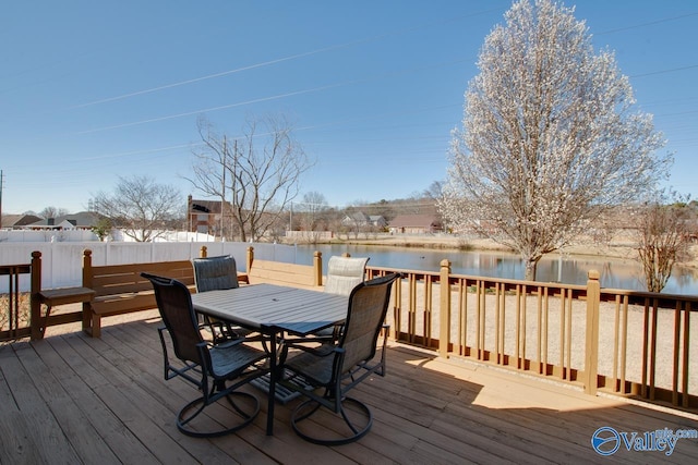 wooden deck featuring outdoor dining space, fence, and a water view