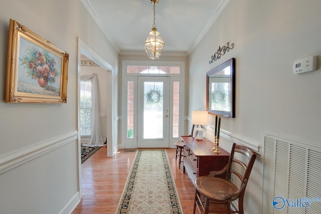 foyer with light wood finished floors, visible vents, plenty of natural light, and ornamental molding