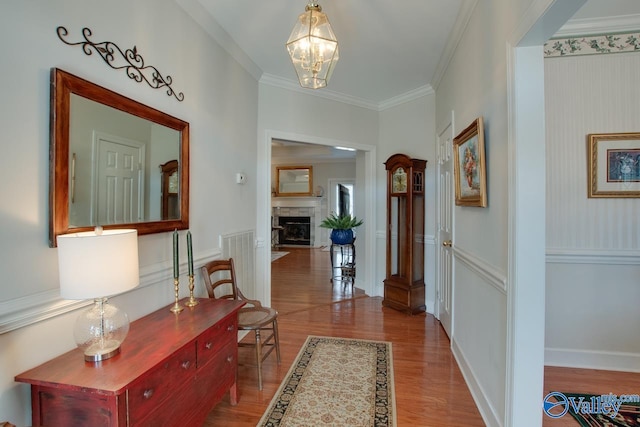 hallway featuring baseboards, a notable chandelier, wood finished floors, and crown molding