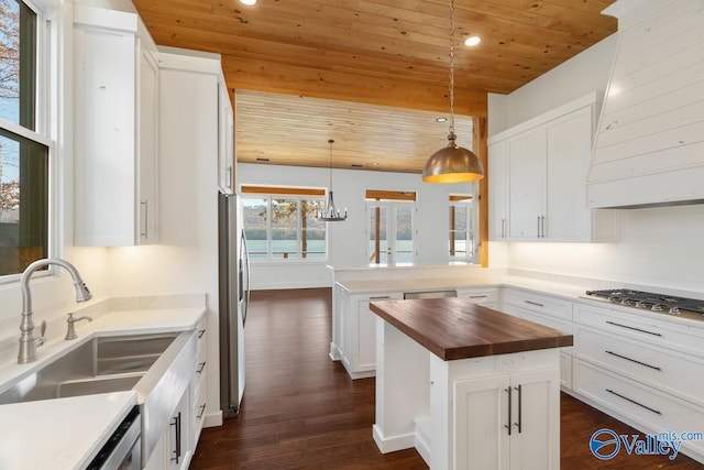 kitchen with wood ceiling, sink, white cabinets, butcher block countertops, and hanging light fixtures