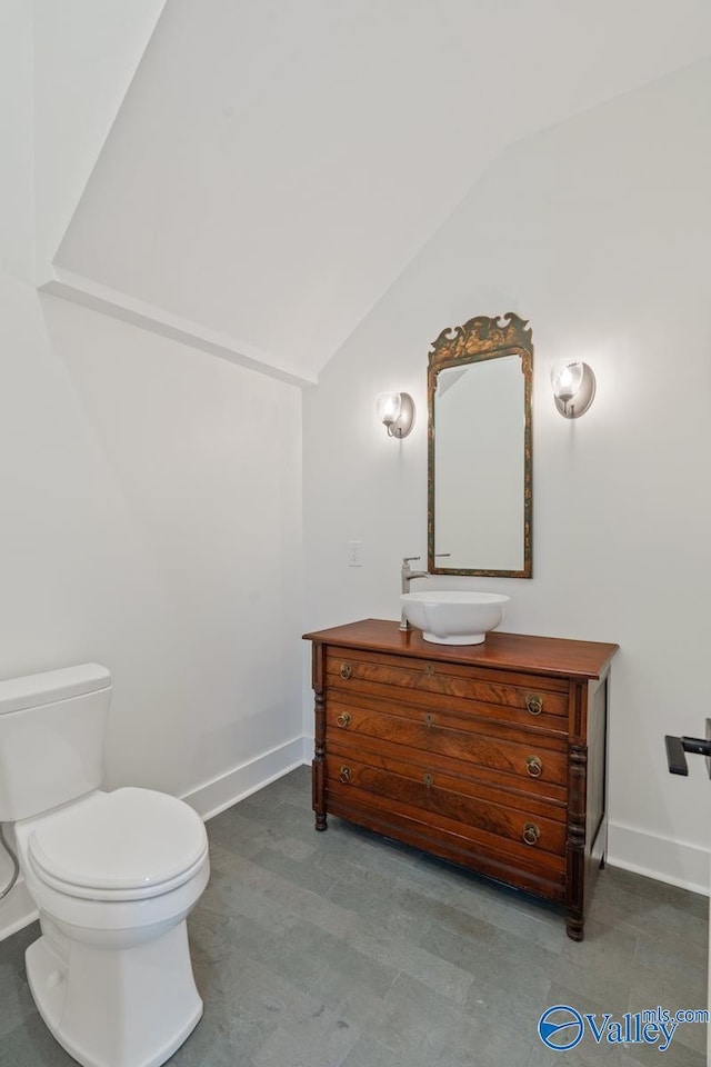 bathroom with vanity, toilet, and lofted ceiling