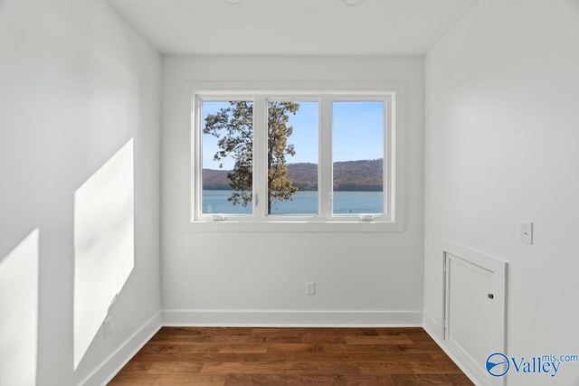 spare room featuring dark hardwood / wood-style floors and a water view