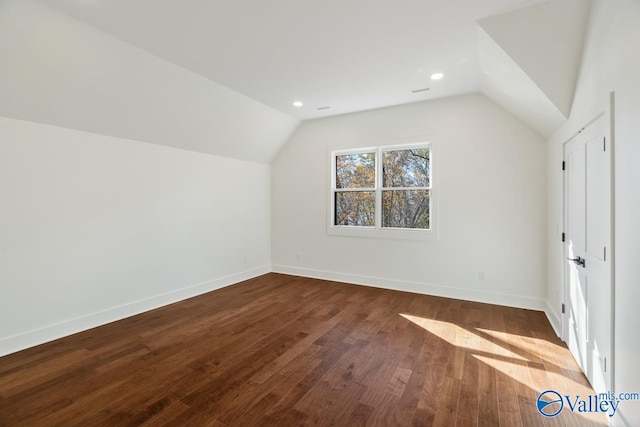 additional living space with hardwood / wood-style floors and vaulted ceiling