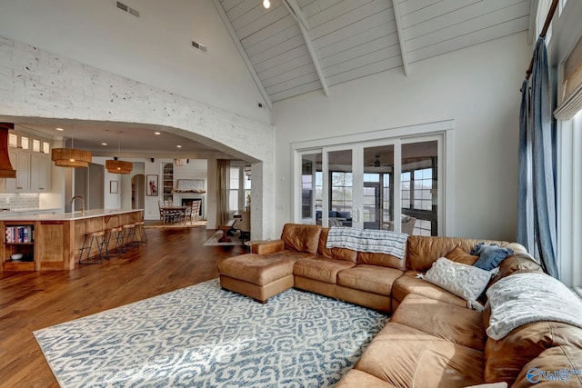 living area with arched walkways, a fireplace, wood finished floors, and visible vents