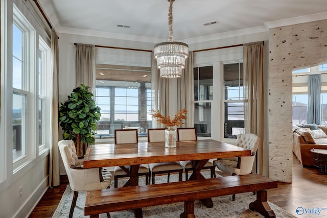 dining room with an inviting chandelier, crown molding, and hardwood / wood-style floors