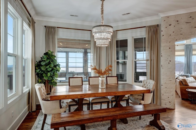dining space featuring crown molding, dark wood finished floors, visible vents, and a notable chandelier