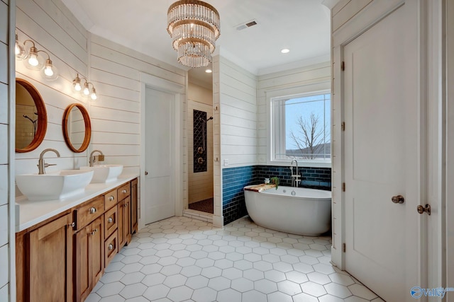full bath featuring a freestanding tub, visible vents, a sink, and double vanity