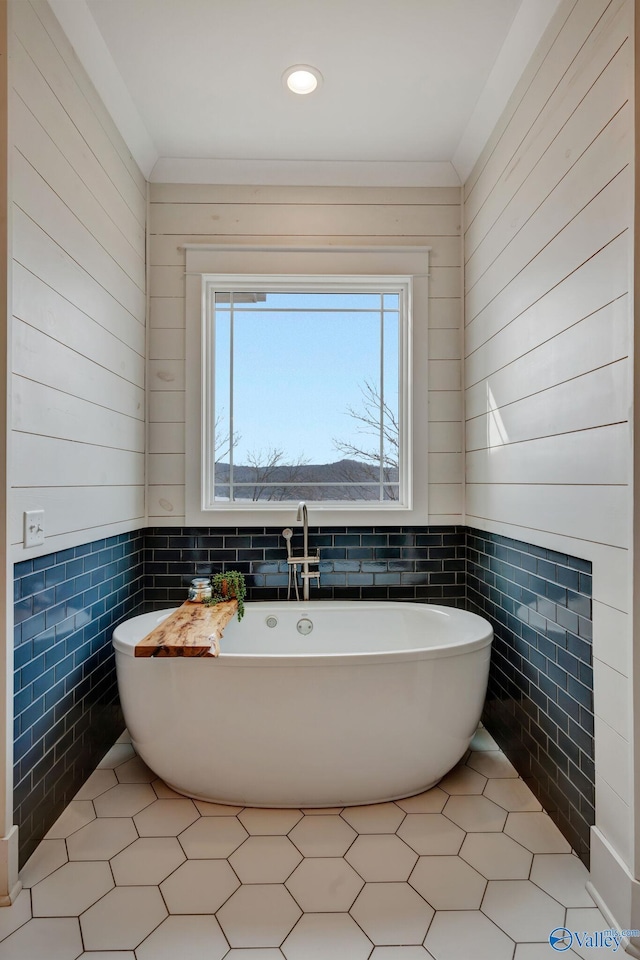 bathroom featuring ornamental molding, a freestanding tub, tile walls, and tile patterned floors
