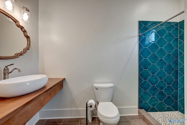 full bath with baseboards, toilet, tile patterned floors, a shower stall, and a sink