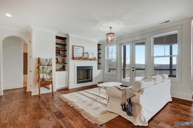 living room featuring dark hardwood / wood-style floors, built in shelves, a notable chandelier, and plenty of natural light