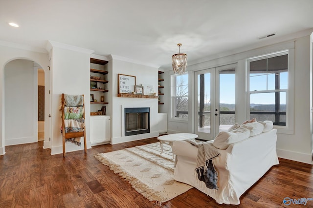 living room featuring arched walkways, a chandelier, dark wood-type flooring, visible vents, and ornamental molding