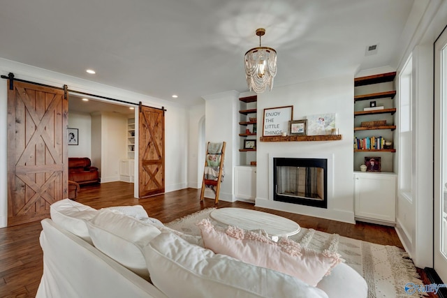 living room featuring a barn door, built in features, dark wood finished floors, and recessed lighting