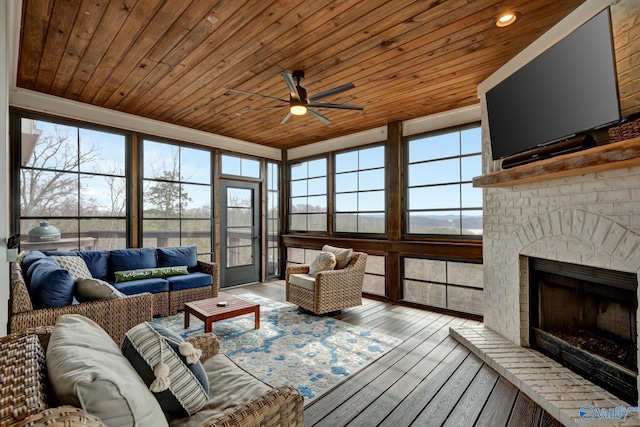 living room featuring ceiling fan, light wood-type flooring, a fireplace, and wooden ceiling