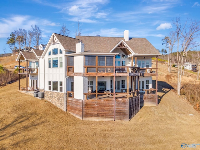 back of property with roof with shingles, a yard, a chimney, board and batten siding, and a wooden deck