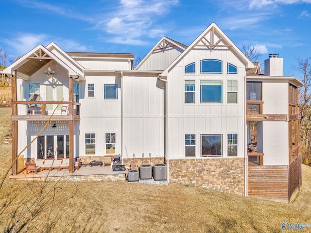rear view of property featuring a chimney, a yard, a balcony, and a patio