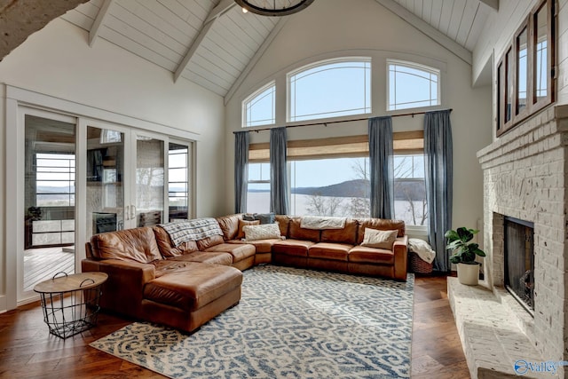 living room featuring high vaulted ceiling, beamed ceiling, a mountain view, a stone fireplace, and dark wood-type flooring