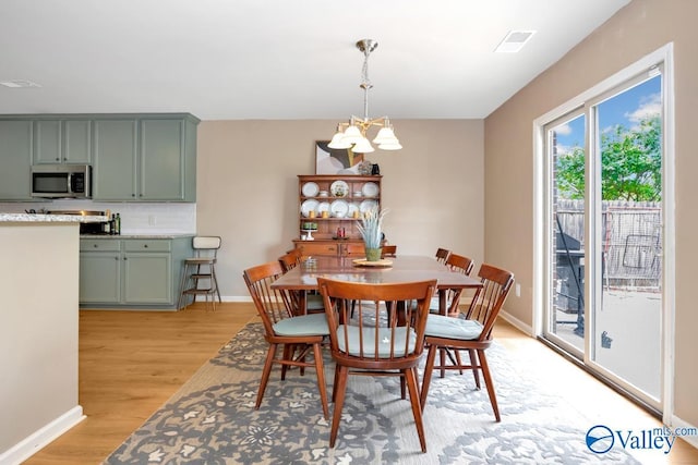 dining space with a chandelier, light wood-style flooring, and baseboards