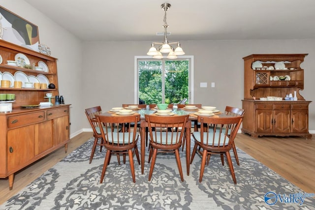 dining space with baseboards, light wood finished floors, visible vents, and a notable chandelier