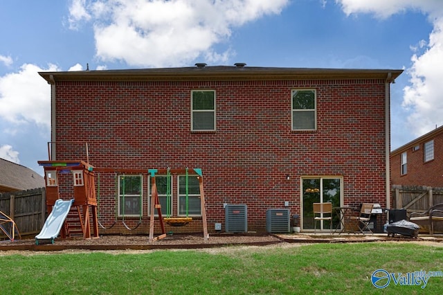 rear view of property featuring central AC, brick siding, a lawn, and fence