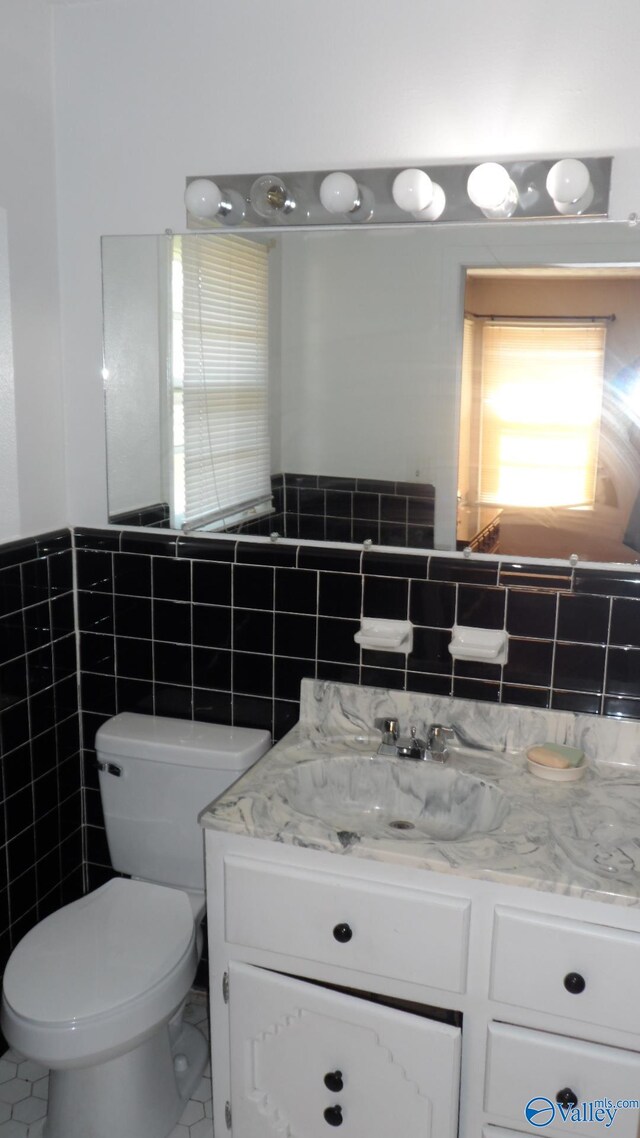 bathroom with vanity, tile walls, and toilet