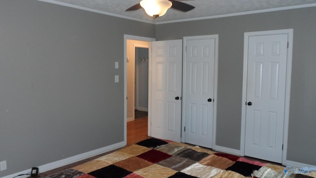 unfurnished bedroom with ceiling fan, ornamental molding, and multiple closets