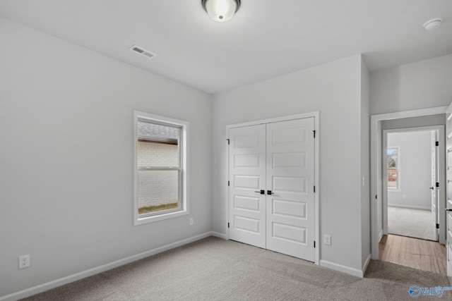 unfurnished bedroom with light colored carpet and a closet