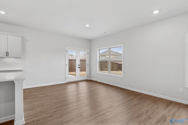 unfurnished living room featuring hardwood / wood-style flooring and french doors