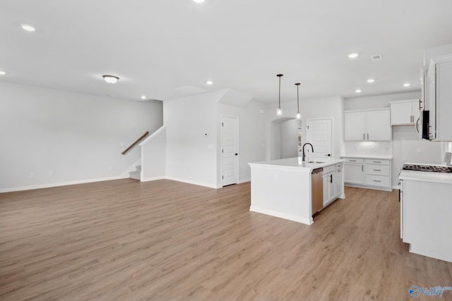 kitchen with white cabinetry, sink, stainless steel appliances, a center island with sink, and light wood-type flooring