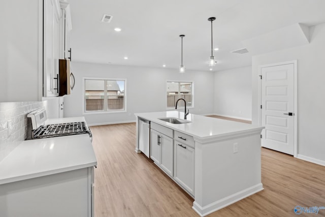 kitchen featuring white cabinetry, a kitchen island with sink, sink, and decorative light fixtures