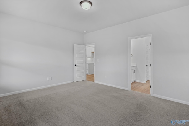 unfurnished bedroom featuring light carpet and ensuite bath