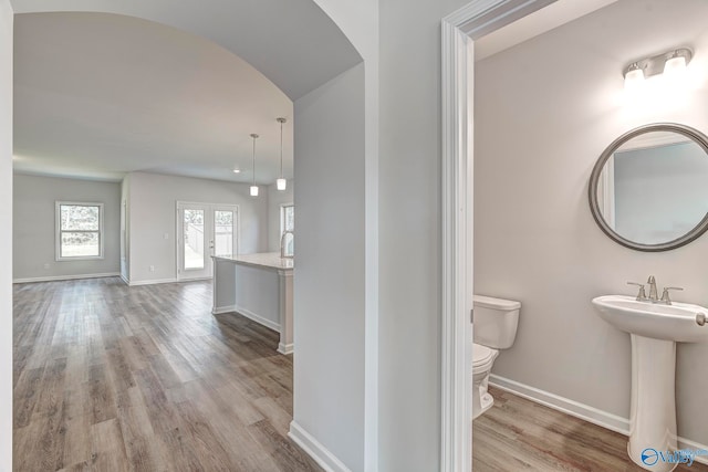 bathroom featuring wood-type flooring, toilet, french doors, and sink