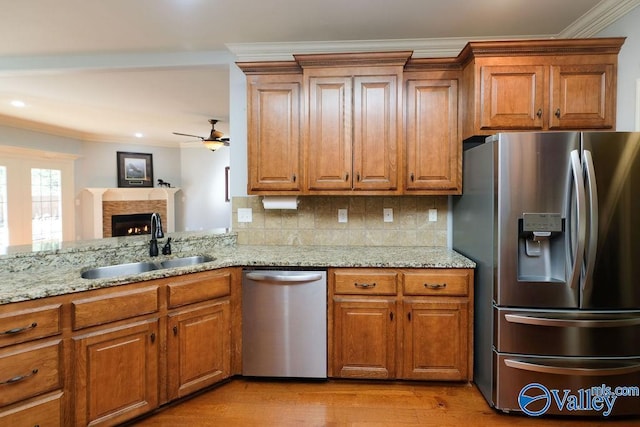 kitchen with ceiling fan, decorative backsplash, sink, stainless steel appliances, and ornamental molding