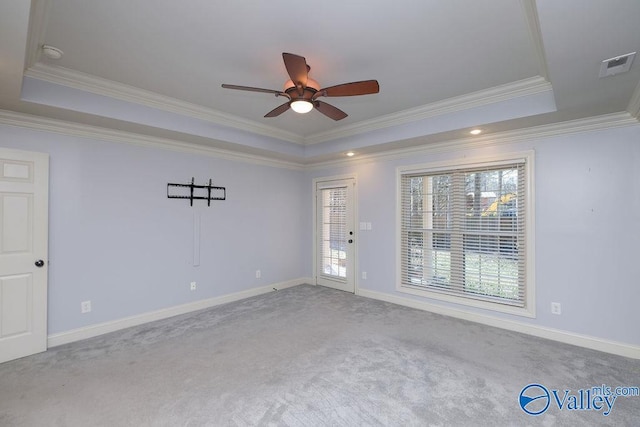 carpeted empty room featuring ceiling fan, a healthy amount of sunlight, and a tray ceiling