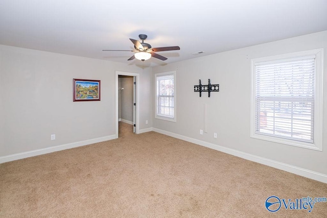 carpeted spare room with ceiling fan and a wealth of natural light