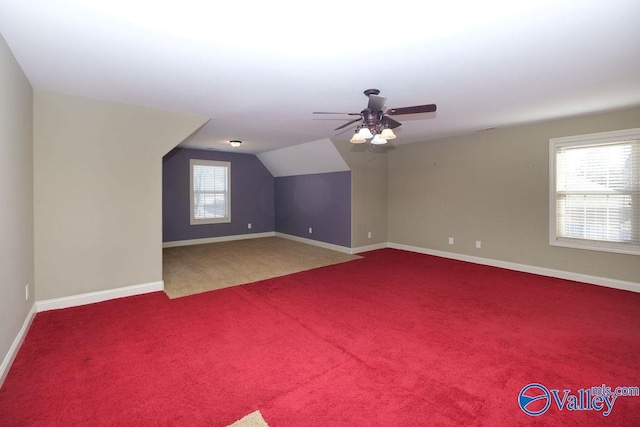 additional living space featuring vaulted ceiling, ceiling fan, carpet flooring, and a healthy amount of sunlight