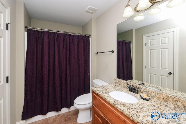 bathroom with toilet, vanity, and tile patterned flooring