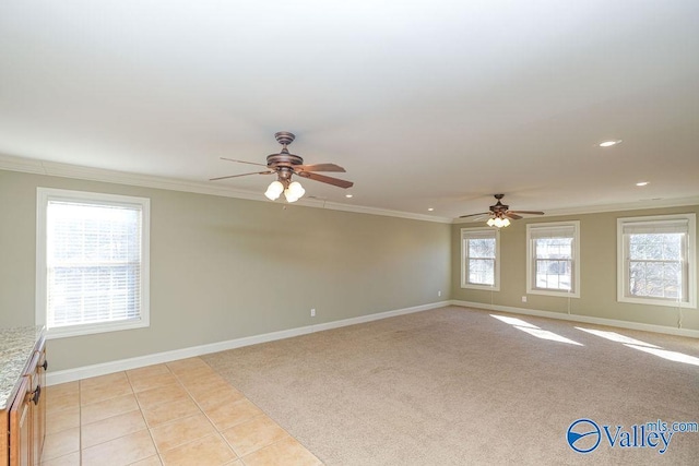 empty room with ceiling fan, light tile patterned floors, a wealth of natural light, and crown molding