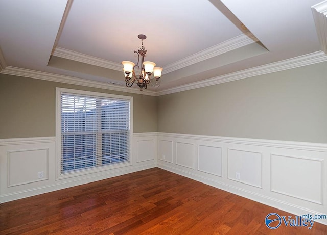 unfurnished room featuring dark wood-type flooring, a tray ceiling, ornamental molding, and a notable chandelier