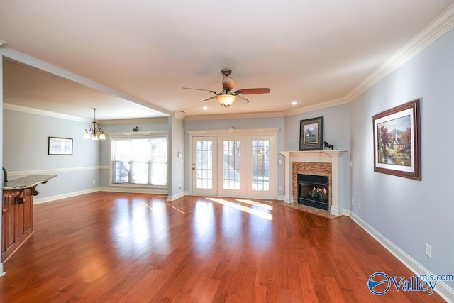 unfurnished living room featuring crown molding, ceiling fan with notable chandelier, and wood-type flooring