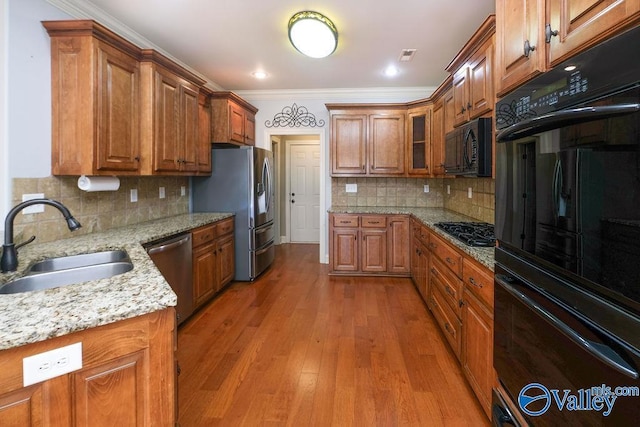 kitchen featuring light stone countertops, sink, black appliances, and crown molding