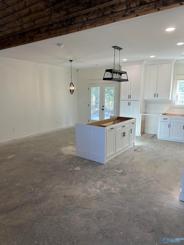 kitchen with wooden counters, hanging light fixtures, and white cabinets