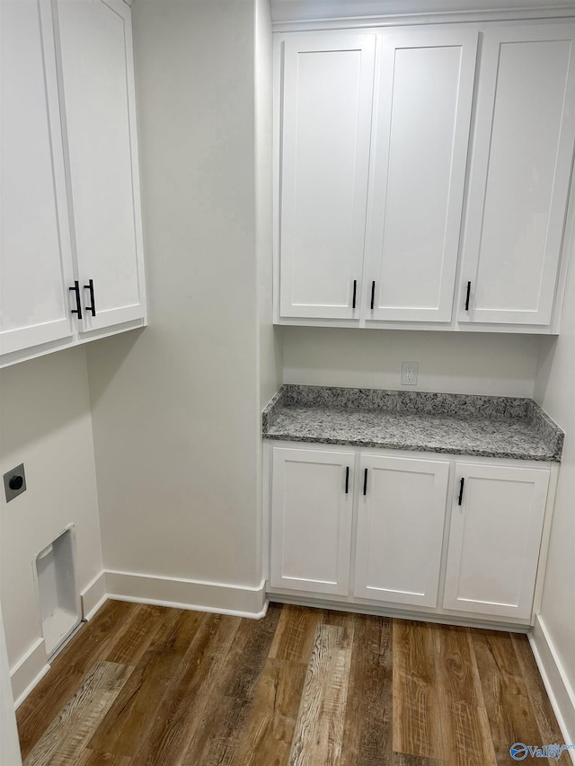 laundry room featuring dark wood finished floors, cabinet space, hookup for an electric dryer, and baseboards