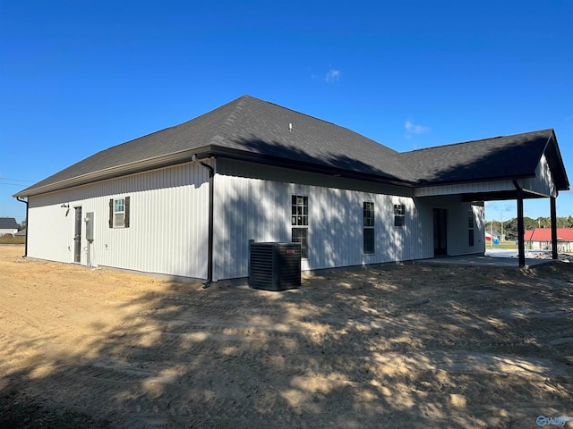 rear view of property with a shingled roof and central AC unit