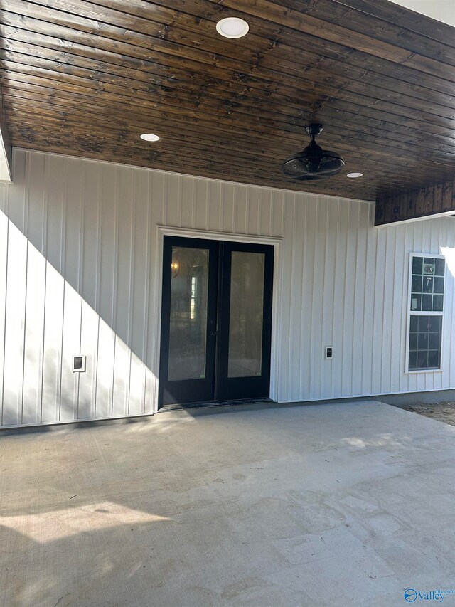 property entrance with board and batten siding, ceiling fan, and a patio